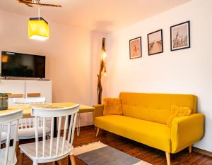a living room with a yellow couch and a table at Domek InoSasino z basenem i sauną in Sasino