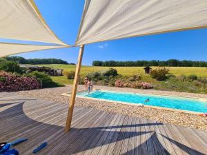 ein großer Regenschirm neben einem Pool in der Unterkunft Domaine d'Escapa in Estipouy