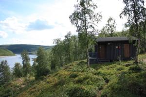 eine Hütte an der Seite eines Hügels neben einem Fluss in der Unterkunft Tenon näköalamökit in Utsjoki
