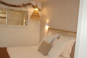 Schlafzimmer mit einem Bett mit weißen Kissen und einem Spiegel in der Unterkunft L'Abri du Marin in Audierne