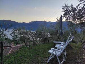 dwa białe krzesła siedzące na wzgórzu z widokiem na jezioro w obiekcie CasaDolcelago Marone Villa con Giardino Vista Lago Private Parking w mieście Marone