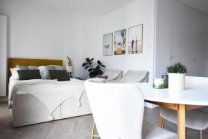 a white bedroom with a bed and a table and chairs at Royal Sand Apartment in Gdańsk