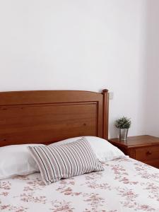 a bed with a wooden headboard and a striped pillow at Casa dos Pinheiros in São Pedro de Moel