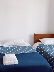 two beds with blue and white sheets with towels on them at Casa dos Pinheiros in São Pedro de Moel