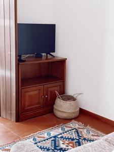 Habitación con TV en un armario con alfombra. en Casa dos Pinheiros en São Pedro de Moel
