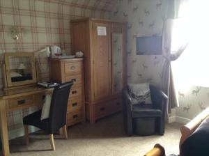 een slaapkamer met een bureau, een stoel en een dressoir bij Hundalee House in Jedburgh