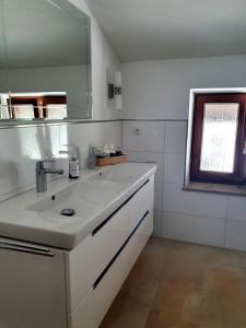 een witte badkamer met een wastafel en een spiegel bij Feinzimmer mit Feinkost & Wein in Marquartstein