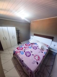 una camera con un letto con una coperta viola e rosa di Aconchego do lar a Gramado