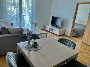 ein Wohnzimmer mit einem Tisch, Stühlen und einem TV in der Unterkunft Küüni Guest Apartment in Tartu