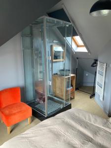 um quarto com um armário de vidro e uma cadeira laranja em Gîte 1908 avec GARAGE em Wimereux