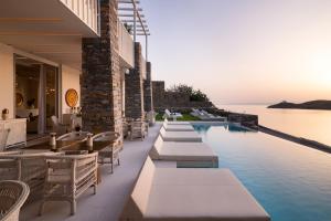 a swimming pool with tables and chairs next to the ocean at Ydor Hotel & Spa by Sandglass in Vourkarion