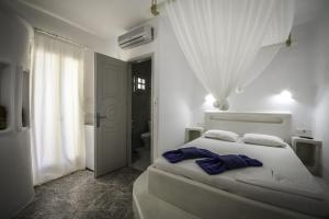 a bedroom with a white bed and a bathroom at Anerousses in Adamantas