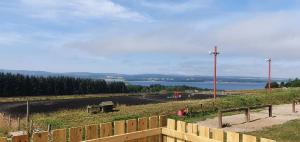 a wooden fence with a view of a lake at The Pod at Hollingwell House - Glamping NC500 Edderton in Balblair