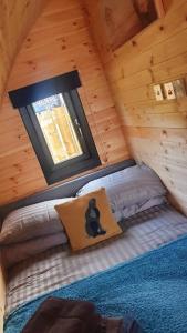 a bed in a wooden cabin with a window at The Pod at Hollingwell House - Glamping NC500 Edderton in Balblair