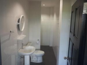 a white bathroom with a toilet and a sink at Living Room Apartments Bang Lut Beach KhaoLak in Bang Sak