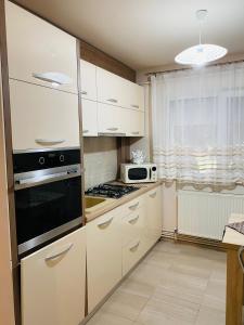 a kitchen with white cabinets and a stove top oven at SELLADA APARTAMENT - Free Private Parking,AC,Wi-Fi in Carei