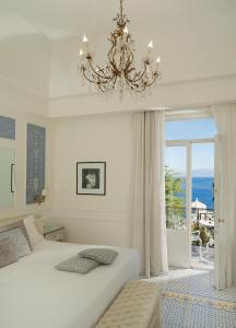 a bedroom with a large white bed and a chandelier at Luxury Villa Excelsior Parco in Capri