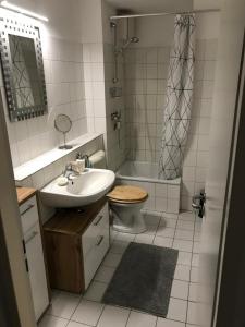 a bathroom with a sink and a toilet and a shower at Stadtwohnung im Zentrum mit 24-7 Self Check-In, WLAN & Smart TV in Kiel