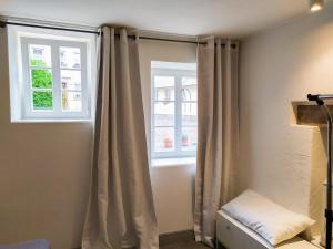 a room with two windows with curtains and a lamp at Living-in-History: Meister Carl Apartment in Dudeldorf