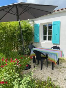 uma mesa e cadeiras debaixo de um guarda-sol num quintal em Le sable chaud em Saint-Pierre-dʼOléron