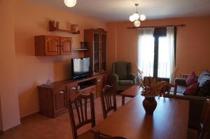 ein Wohnzimmer mit einem Esstisch und einem TV in der Unterkunft APARTAMENTOS LAS ERAS in El Negredo