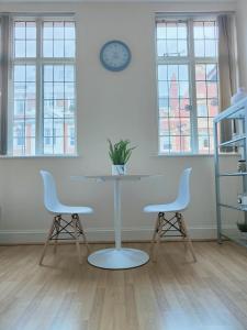 een tafel en twee stoelen in een kamer met een klok aan de muur bij Newhall Street Place in Birmingham