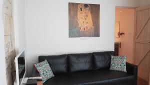 a black leather couch in a living room with a painting at Aan de Cauberg in Valkenburg