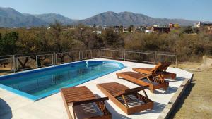a swimming pool with a bunch of chairs at Country House Trabun Curev in Capilla del Monte