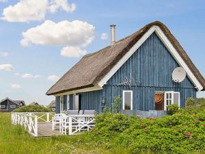 a blue house with a thatched roof and a deck at 4 person holiday home in Harbo re in Harboør