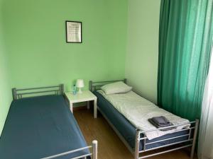 two beds in a small room with green curtains at Tanie Spanie in Międzylesie