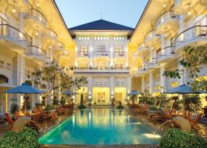 日惹The Phoenix Hotel Yogyakarta - Handwritten Collection的一座带桌子和遮阳伞的室内游泳池
