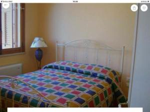 マルサラにあるMARSALA - Appartamento per vacanze di fronte Isola di Mothyaのベッドルームにカラフルな掛け布団付きのベッド1台
