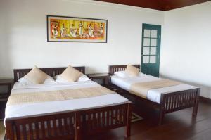 two beds in a room with a picture on the wall at Sir John's Bungalow in Matale