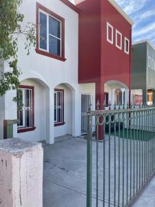 a white and red house with a fence at Montecarlo 2 in Rosarito