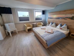 a bedroom with a large bed and two windows at Hotel Norden Norddeich in Norddeich