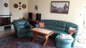 a living room with a green couch and a table at Bismarckhöhe Tharandt in Tharandt