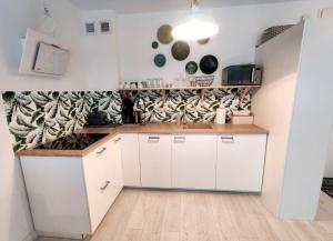 kuchnia z białymi szafkami i drewnianą podłogą w obiekcie Apartament Słoneczny Brzeg w Kołobrzegu