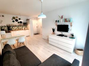 salon z kanapą i telewizorem z płaskim ekranem w obiekcie Apartament Słoneczny Brzeg w Kołobrzegu