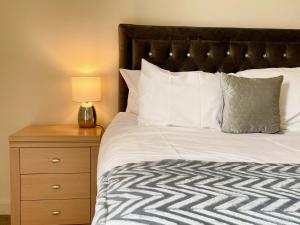 a bed with white sheets and a nightstand with a lamp at Central Darlington Central 2BR Apartment in Darlington