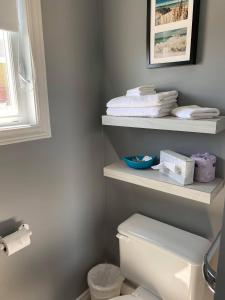 a bathroom with a toilet and shelves with towels at Motel Glenn in Perce