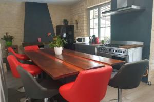 une cuisine avec une table en bois et des chaises rouges dans l'établissement Magnifique maison périgourdine avec piscine, à Sarlat-la-Canéda