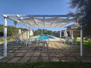 a white pergola over a patio with a table and chairs at Villa Valeria in Floridia