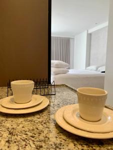 two cups and plates on a counter in a bedroom at Manaíra Apart Hotel in João Pessoa