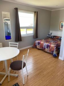 a bedroom with a bed and a table and chair at Motel Glenn in Perce