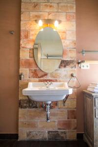 La salle de bains est pourvue d'un lavabo et d'un miroir sur un mur en briques. dans l'établissement Slowcameros Duplex Ortigosa, à Ortigosa