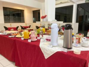 ein Tisch mit einer roten Tischdecke, auf der Essen stand in der Unterkunft Domum Hotel in Pindamonhangaba