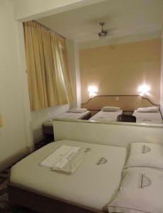 um pequeno quarto com 3 camas e um espelho em Hotel Belas Artes no Rio de Janeiro