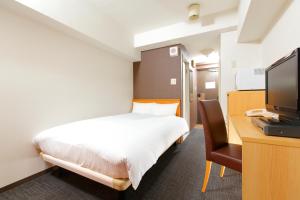 a bedroom with a bed and a desk with a television at FLEXSTAY INN Shirogane in Tokyo