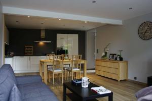 ein Wohnzimmer mit Couch und Tisch und eine Küche in der Unterkunft Maison à deux pas du circuit in Stavelot