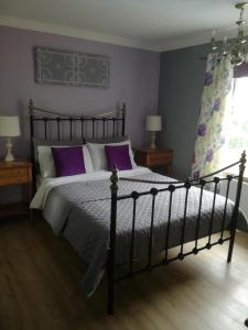 a bedroom with a large bed with purple pillows at Meadow Farm Cottage in Norwich